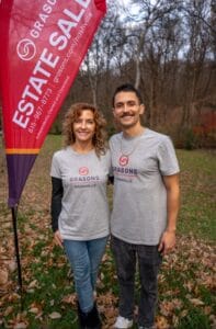 Grasons Nashville team members standing by a red Grasons Estate Sale outdoor flag